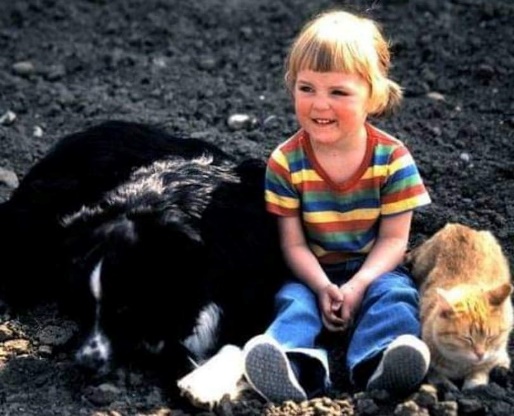 Child sitting between a dog and a cat
